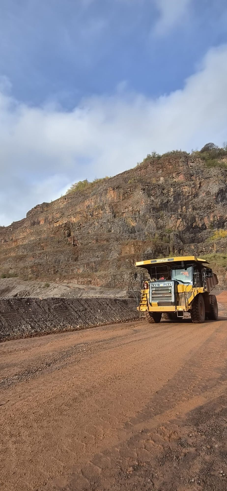 Dump truck on a haul road beneath the stepped quarry face