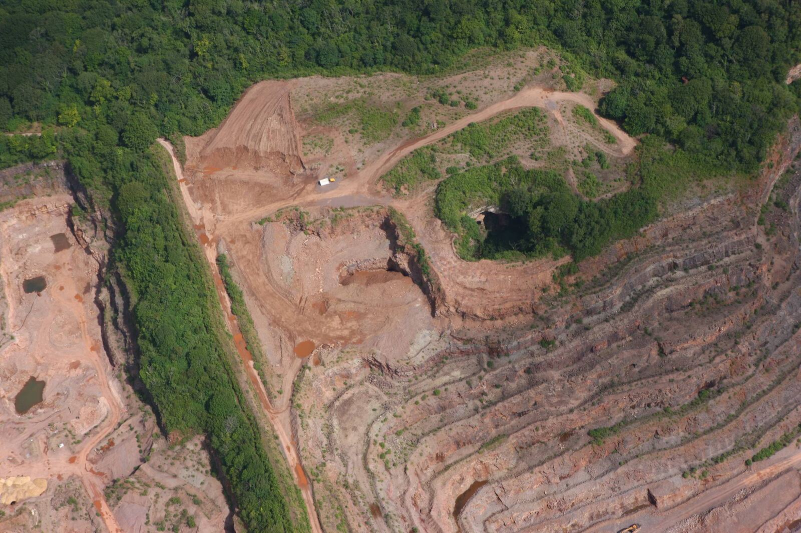 Close aerial view of the stepped quarry faces and haul roads at Taffs Well Quarry
